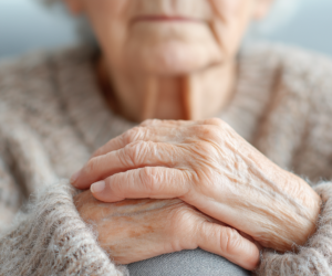 u8868829498_Elderly_woman_sitting_alone_with_hands_folded_on_la_de80025d-d5f6-4d11-854d-d143a936728e